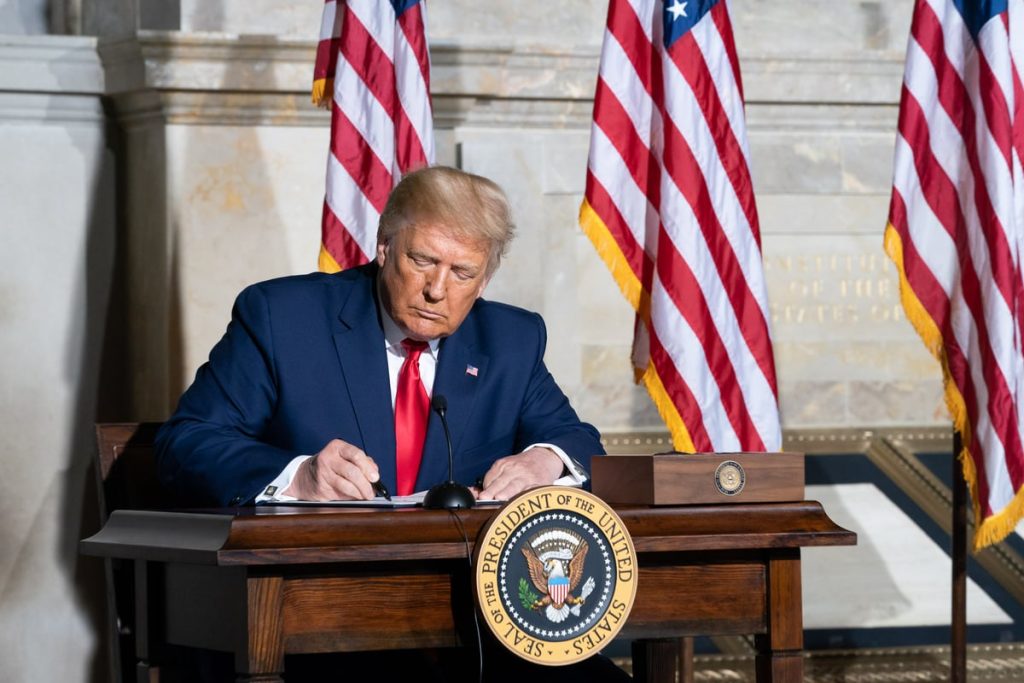President Donald J. Trump signs a document.