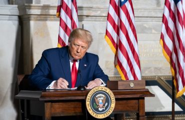 President Donald J. Trump signs a document.