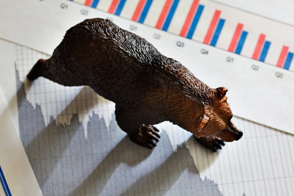 A bear walks across stock price charts.
